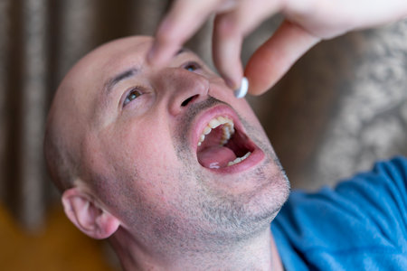 Extreme closeup man face taking white pill, mouth view swallowing pills, illness. man take...