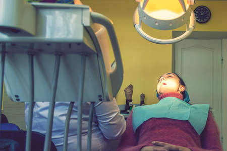Male dentists examining and working on young female patient. Real woman in a chair at the dentist....