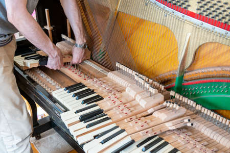 Setting up an old piano. The master repairs an old piano. Deep cleaning the piano. Hands of professional worker repairing and tuning an old piano. toned.の写真素材