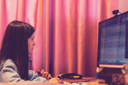 Smart preteen schoolgirl doing her homework with digital tablet at home. Child using gadgets to study. Education and learning for kids. Homeschooling during quarantine. toned. selected focus.の写真素材