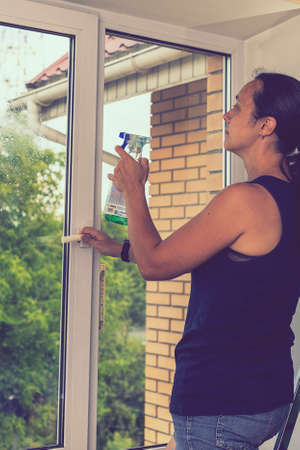 Beautiful woman cleaning window at home. A girl washes windows at home. To clean up the house....