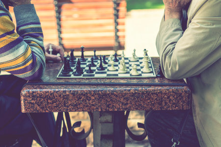 Two old men playing chess. Active retired people, old friends and free time. Active retired people old friends and free time two senior men having fun and playing chess at park. blurry. tonedの写真素材