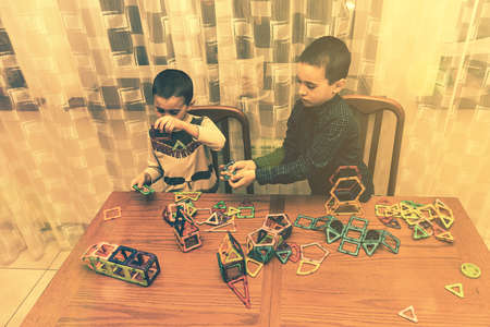 Children Boys playing with construction set on the floor.Educational games for kids. Boys playing whit blocks. Kindergarten. tonedの写真素材