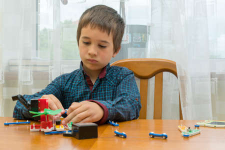 The boy playing an electric constructor. The child is played by intellectual toys. A boy in a blue shirt masters electronics. The concept of early development of children. tonedの写真素材