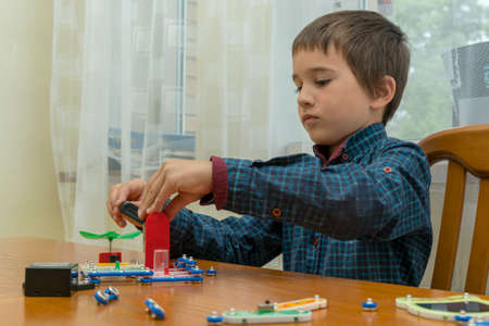 The boy playing an electric constructor. The child is played by intellectual toys. A boy in a blue shirt masters electronics. The concept of early development of children. tonedの写真素材