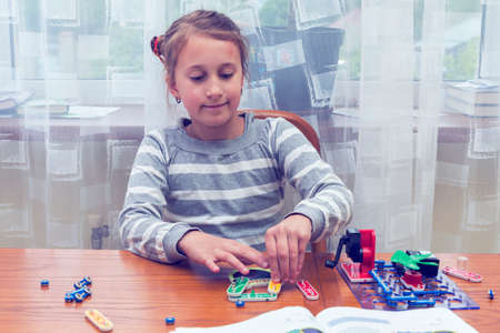 Positive lady playing with toy. She making it from constructor. Entertainment concept. Education, children, technology, science and futuristic concept. E-learning. tonedの写真素材