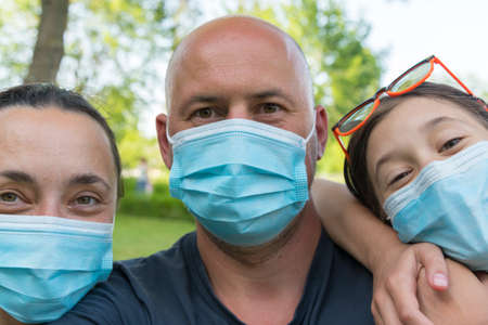 Family in protective medical masks. Mother, father, daughter protect themselves from the virus Coronavirus. Family in medical masks outdoors. close upの写真素材