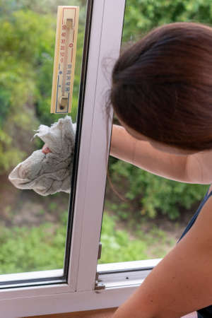 Beautiful woman cleaning window at home. A girl washes windows at home. To clean up the house....