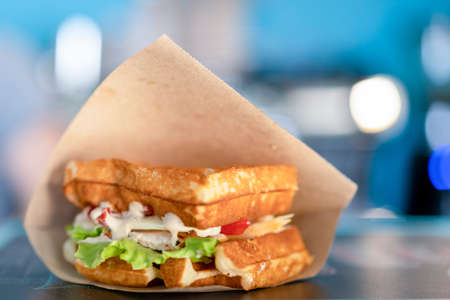 Sandwich in a paper bag close-up. Sandwich filet americain, close up of burger. Fast, but unhealthy foodの写真素材