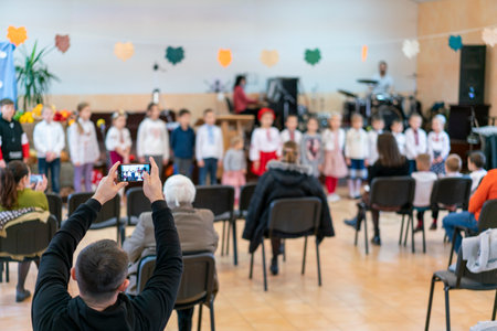 Parents at the performance of children in kindergarten or school. Children on stage. Many parents are watching the kids performance in the hall during Chistmas holiday, blurの写真素材