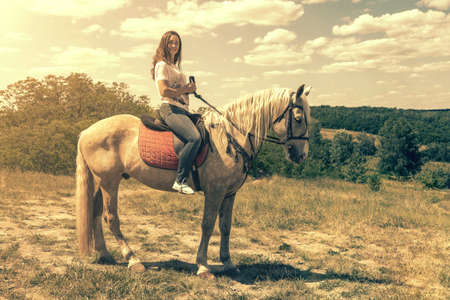 the rider on the white horse. Young horsewoman riding on white horse, outdoors view. girl on white horse runs free. tonedの写真素材