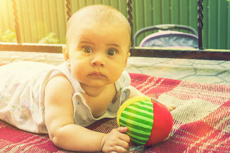 Adorable baby boy learning to crawl and playing with colorful rainbow ball toy. Cute laughing child crawling on a play mat. Nursery, clothing and toys for little kids. tonedの写真素材