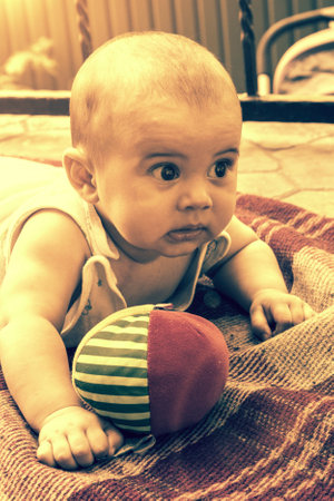 Adorable baby boy learning to crawl and playing with colorful rainbow ball toy. Cute laughing child crawling on a play mat. Nursery, clothing and toys for little kids. tonedの写真素材