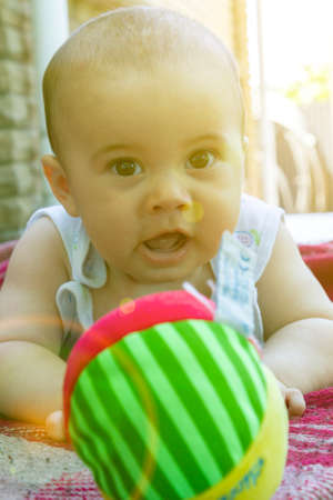 Adorable baby boy learning to crawl and playing with colorful rainbow ball toy. Cute laughing child crawling on a play mat. Nursery, clothing and toys for little kids. tonedの写真素材