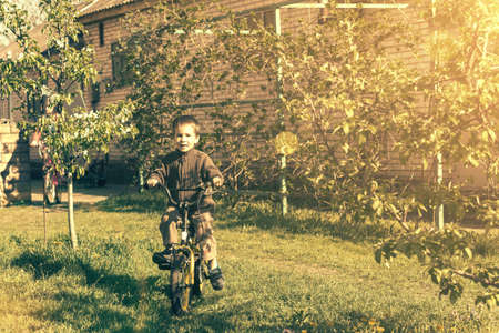 Happy kid boy of 5 years having fun in spring park with a bicycle. Boy learning to ride his bike. tonedの写真素材