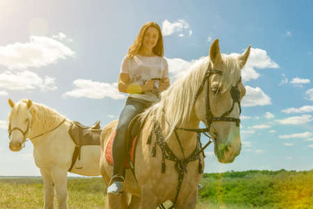 the rider on the white horse. Young horsewoman riding on white horse, outdoors view. girl on white horse runs free. tonedの写真素材