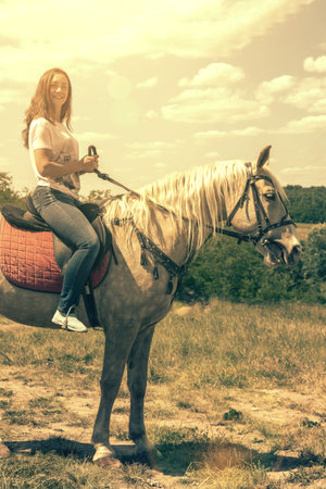 the rider on the white horse. Young horsewoman riding on white horse, outdoors view. girl on white horse runs free. tonedの写真素材