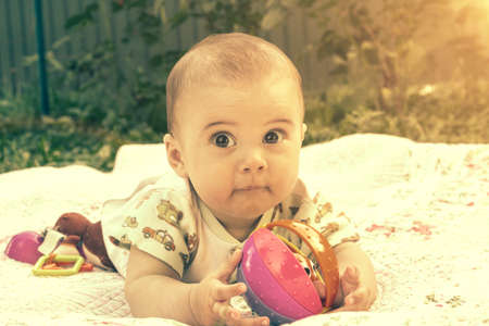 Adorable baby boy learning to crawl and playing with colorful rainbow ball toy. Cute laughing child crawling on a play mat. Nursery, clothing and toys for little kids. tonedの写真素材