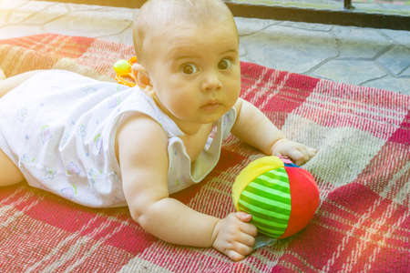 Adorable baby boy learning to crawl and playing with colorful rainbow ball toy. Cute laughing child crawling on a play mat. Nursery, clothing and toys for little kids. tonedの写真素材