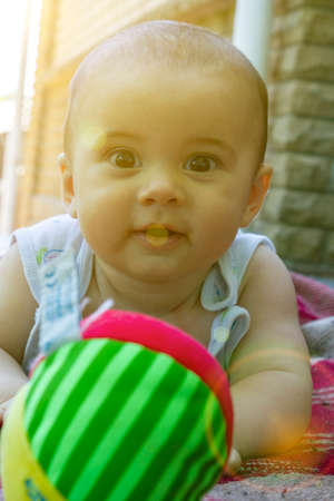 Adorable baby boy learning to crawl and playing with colorful rainbow ball toy. Cute laughing child crawling on a play mat. Nursery, clothing and toys for little kids. tonedの写真素材