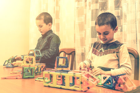 Children Boys playing with construction set on the floor.Educational games for kids. Boys playing whit blocks. Kindergarten. tonedの写真素材