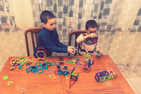 Children Boys playing with construction set on the floor.Educational games for kids. Boys playing whit blocks. Kindergarten. tonedの写真素材