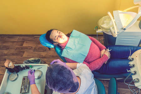 Male dentists examining and working on young female patient.Dentists office. Real woman in a chair at the dentist. tonedの写真素材