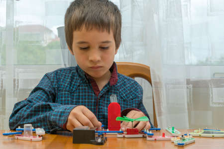 The boy playing an electric constructor. The child is played by intellectual toys. A boy in a blue shirt masters electronics. The concept of early development of childrenの写真素材