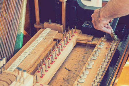 Setting up an old piano. The master repairs an old piano. Deep cleaning the piano. Hands of professional worker repairing and tuning an old piano. tonedの写真素材