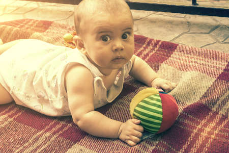Adorable baby boy learning to crawl and playing with colorful rainbow ball toy. Cute laughing child crawling on a play mat. Nursery, clothing and toys for little kids. tonedの写真素材
