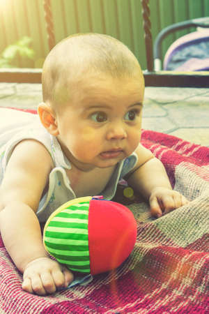 Adorable baby boy learning to crawl and playing with colorful rainbow ball toy. Cute laughing child crawling on a play mat. Nursery, clothing and toys for little kids. tonedの写真素材