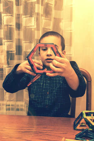 little smiling boy playing with magnetic constructor toy. Cute little boy playing with colorful magnetic constructor toy. tonedの写真素材