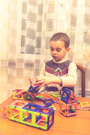 little smiling boy playing with magnetic constructor toy. Cute little boy playing with colorful magnetic constructor toy. tonedの写真素材