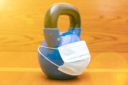 kettlebells on gym with blue surgical mask. Close up. Sports kettlebell in the gym, top view. kettlebell wearing blue medical mask. toned. copy space. tonedの写真素材