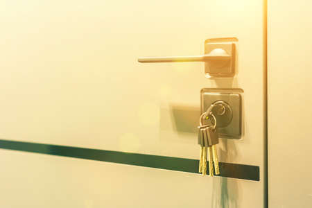 Keys stuck in a lock. closeup Door lock keys, Real estate concept door handle, Key insert and hold in metallic knob on white door horizontal. tonedの写真素材