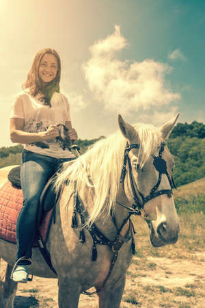 the rider on the white horse. Young horsewoman riding on white horse, outdoors view. girl on white horse runs free. tonedの写真素材