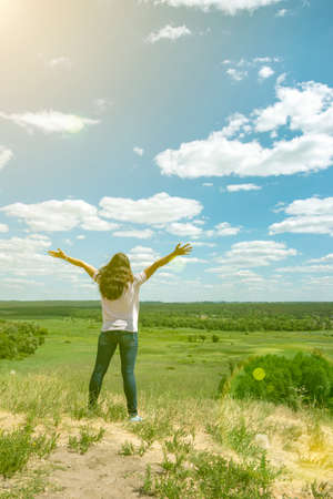 Young woman standing in a wheat field with sunrise on the background. A view from the back of a women standing on a mountain and admires the beautiful view sunset. tonedの写真素材