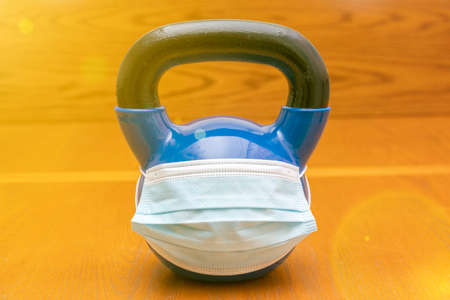 kettlebells on gym with blue surgical mask. Close up. Sports kettlebell in the gym, top view. kettlebell wearing blue medical mask. toned. copy space. tonedの写真素材