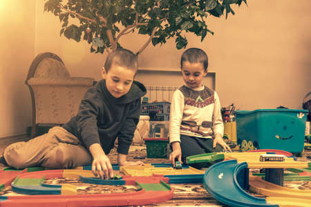 Children Boys playing with construction set on the floor.Educational games for kids. Boys playing whit blocks. Kindergarten. tonedの写真素材