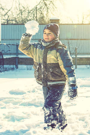 Baby boy walking at snowfall. Child in winter clothes playing with snow. boy making snowball outdoor. Boy playing snowballs in winter park. Christmas winter fun. tonedの写真素材