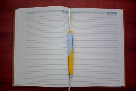 Blank open notebook with pen on wooden deskの写真素材