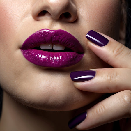 Beautiful female lips with purple nail polish. Closeup portrait of a beautiful young woman with purple manicure.の写真素材