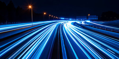 Bright blue light trails weave through a busy highway at night, showcasing the fast movement of vehicles. Streetlights line the road, adding to the dynamic atmosphere of the urban landscape.の写真素材