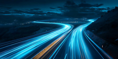 A dynamic view of a winding highway at night, featuring streaks of blue light from vehicles on the...