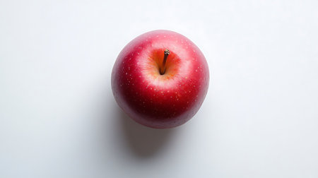 Overhead view of a delicious looking ripe red apple against a plain white backdrop Fresh and...