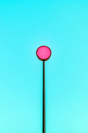 Pink light on a pole stands out against a bright blue sky offering a stark contrast in color and form.の写真素材