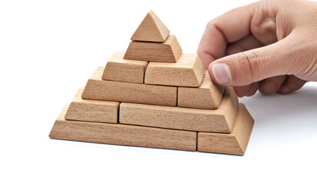 Hand building a wooden block pyramid A symbol of building success hierarchy or achievement.の写真素材