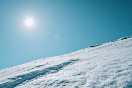 Snowy mountain slope under a bright sun contrasting textures and serene winter landscape Crisp air and natural light.の写真素材