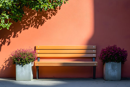 A bench sits in front of a terracotta-colored wall with shadows and plants on each side.の写真素材