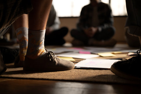 Ground-level group brainstorm focused on strategy with diagrams post-it notes and casual footwear.の写真素材